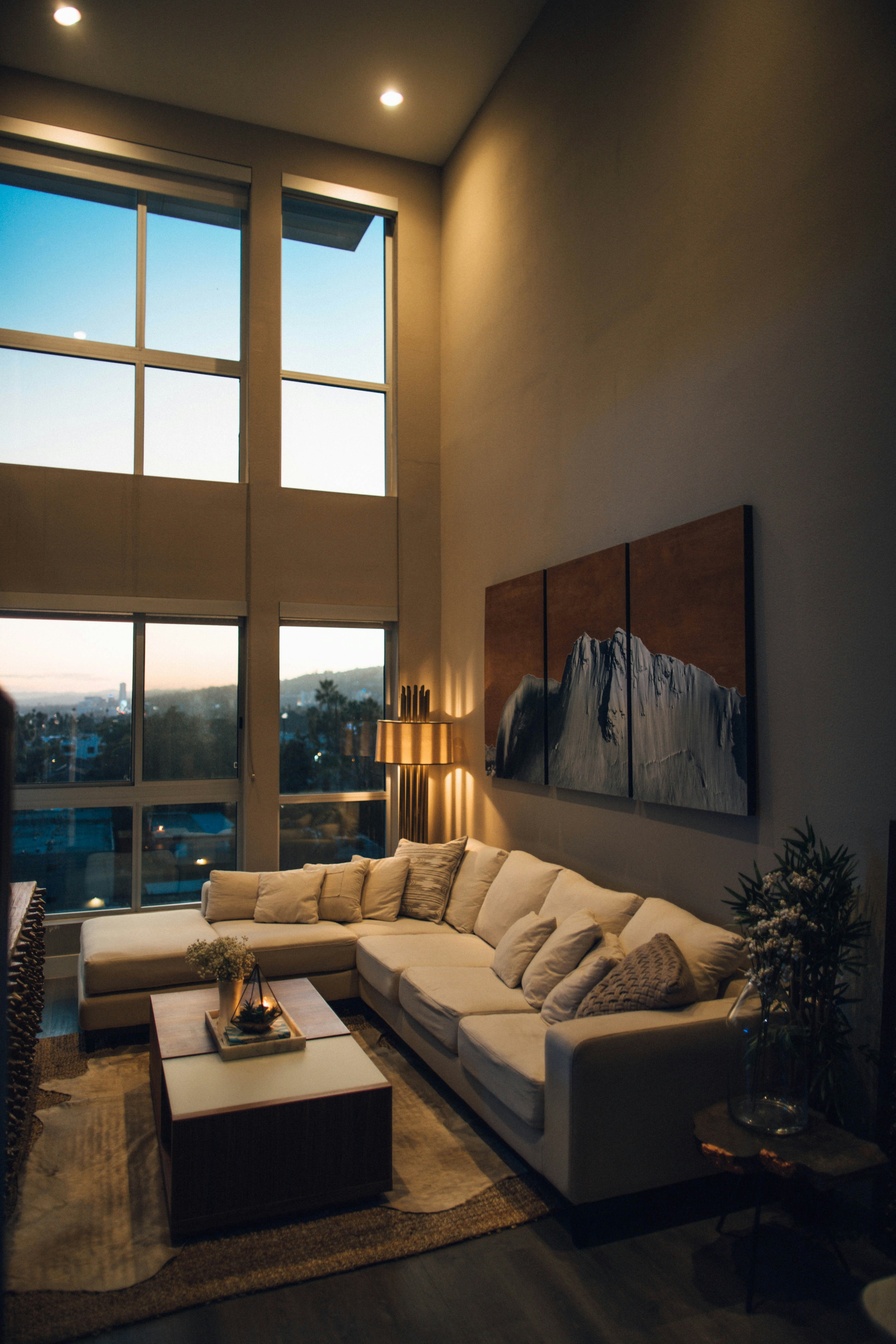 A living room with floor-to-ceiling windows at dusk